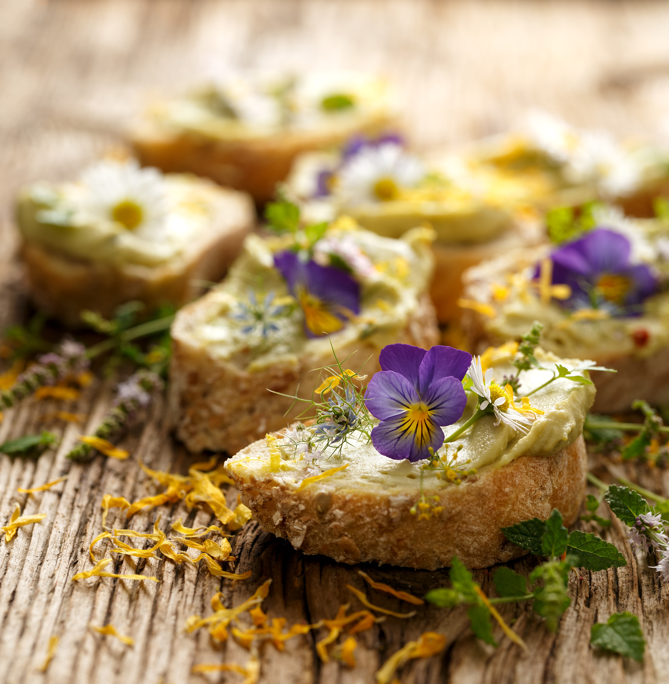 Canapes with eddible flowers and broad bean hummus on a wooden table