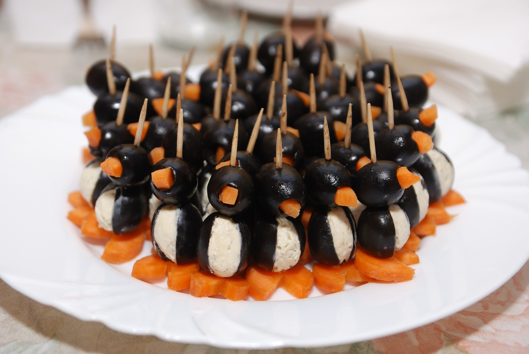 Canapes in the form of a penguin from olives carrots and cottage cheese