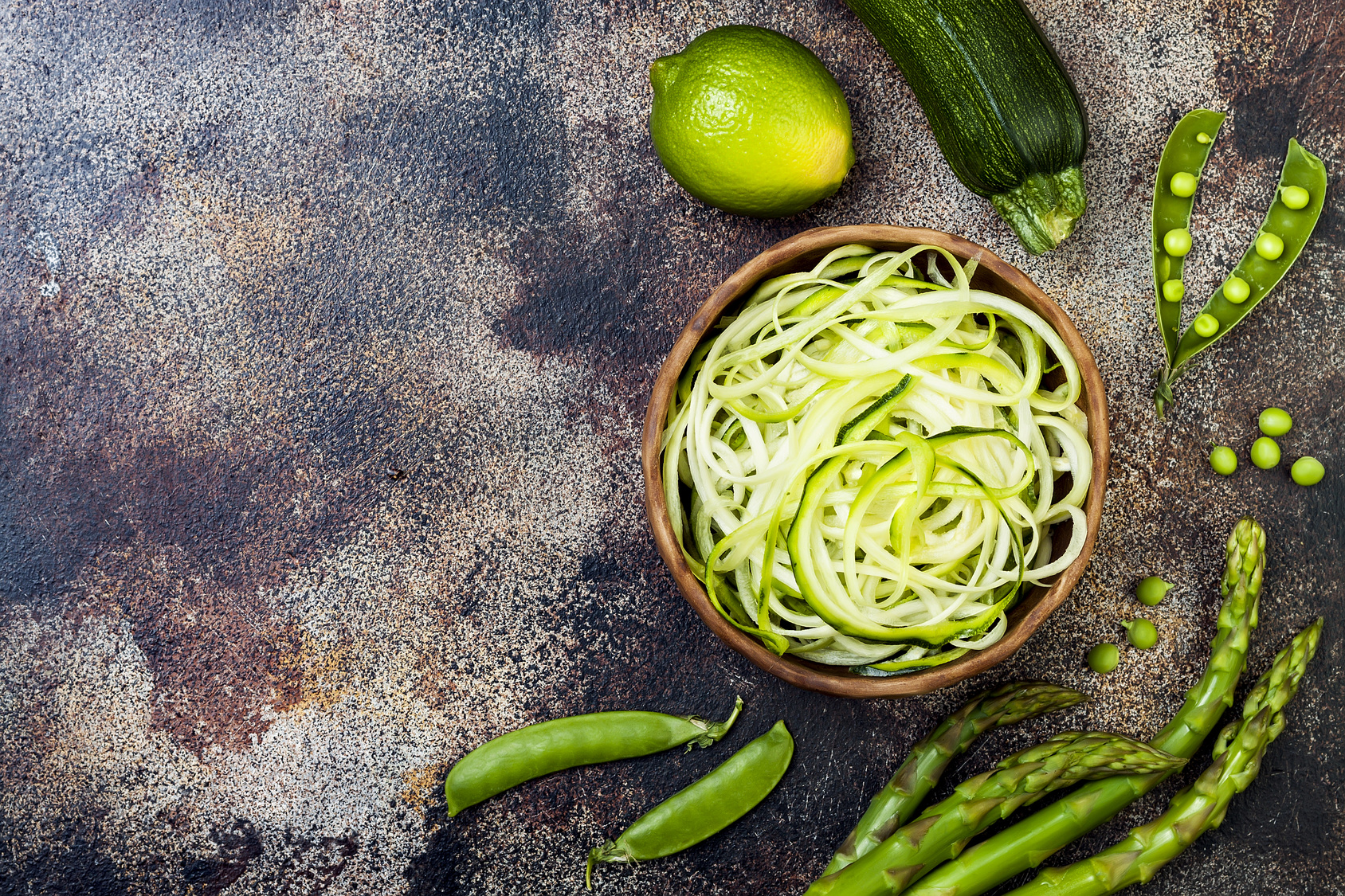 Zucchini spaghetti or noodles (zoodles) bowl with green veggies. Top view, overhead, copy space